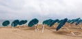 Bowed umbrellas stand on the beach.