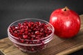 A bowel of pomegranate seeds beside a whole pomegranate fruit. Royalty Free Stock Photo