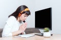 A bowing woman sitting at the table looks at the monitor with a blank black screen and shows a sign of thanks