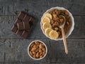 A bowl of almonds, a piece of chocolate and quinoa porridge on a wooden table. Flat lay.