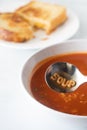 A bowl of alphabet tomato soup with the word soup spelled out in the spoon.