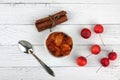Bowl of apple jam, red apples, spoon and cinnamon sticks on white wooden background flat lay