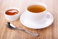 Bowl with apricot jam, cup of tea on saucer, spoon on table Royalty Free Stock Photo