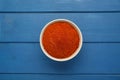 Bowl with aromatic paprika powder on blue wooden table, top view Royalty Free Stock Photo