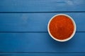 Bowl with aromatic paprika powder on blue wooden table, top view. Space for text Royalty Free Stock Photo