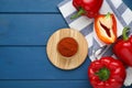 Bowl with aromatic paprika powder and fresh bell peppers on blue wooden table, flat lay. Space for text Royalty Free Stock Photo