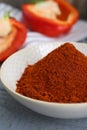 Bowl with aromatic paprika powder and fresh bell peppers on grey wooden table, closeup Royalty Free Stock Photo