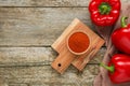 Bowl with aromatic paprika powder and fresh bell peppers on old wooden table, flat lay. Space for text Royalty Free Stock Photo