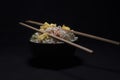 A bowl of asteamed noodles and vegetables decorated with veggies and chopsticks in a black copy space background Royalty Free Stock Photo