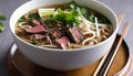A bowl of beef noodle soup with chopsticks