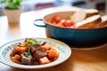 bowl of beef stew, a loaf of sourdough bread beside it