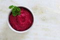 Bowl of beet hummus dip, above view on a white marble background