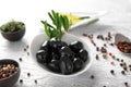 Bowl with black olives covered with oil and spices on table