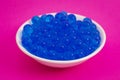 A Bowl of Blue Popping Boba Pearls on a Bright Pink Background