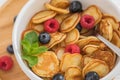 Bowl for breakfast with tiny pancake cereal with blueberries, raspberries, mint Royalty Free Stock Photo