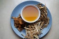 Bowl of brewed chinese herbs with dried assorted roots aside.