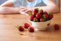 A bowl of bright red strawberries plucked from the garden stands on a wooden table. Royalty Free Stock Photo