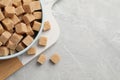 Bowl of brown sugar cubes on light grey marble table, top view. Space for text Royalty Free Stock Photo