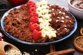 Bowl of cacao oatmeal porridge with banana, raspberries coconut and caramel sauce on rustic table, hot and healthy food for