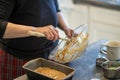 Bowl of cake bread batter in a big glass bowl with a wooden spoon being scraped into metal loaf pan. Royalty Free Stock Photo