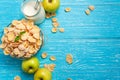 Bowl cereal on blue wooden table with fresh apple and milk near. Royalty Free Stock Photo