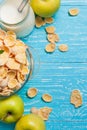 Bowl cereal on blue wooden table with fresh apple and milk near. Royalty Free Stock Photo