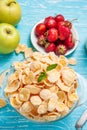 Bowl of cereal on a blue wooden table and fresh strawberry, apple behind. Royalty Free Stock Photo