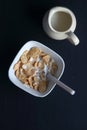 Bowl of cereal, cornflakes with milk in a bowl on a black background