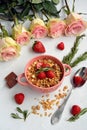 Bowl with cereal, strawberries, spoon, chocolate and roses on a light background, top view Royalty Free Stock Photo