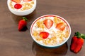 Bowl with cereal, strawberry and milk on a wooden surface