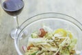 Bowl of cheese vegetable salad and glass of red wine placed on wooden table Royalty Free Stock Photo