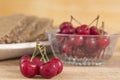 bowl of cherries and bread tray, in the foreground a small cluster with five cherries