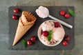 Bowl of cherry chocolate ice cream, above scene with cones on slate