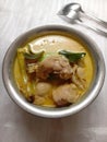 A bowl of chicken curry on a white table