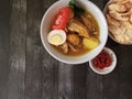 A bowl of chicken soup on a dark background