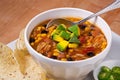 Bowl of chicken taco soup with tortilla chips in a white bowl and plate