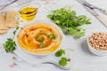 A bowl of chickpeas homemade hummus with olive oil, cilantro and smoked paprika on white wooden background