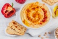 A bowl of chickpeas homemade hummus with olive oil, crispbread and smoked paprika on white background