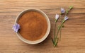 Bowl of chicory powder and flowers on wooden table, flat lay