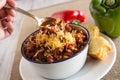 Bowl of Chili With Corn Bread Muffin Hand Scooping Horizontal