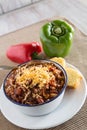 Bowl of Chili With Corn Bread Muffin And Peppers Vertical