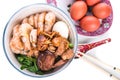 Bowl of Chinese birthday noodle with seafood, meat, red eggs