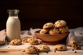 A bowl of chocolate chip cookies sits on a wooden table next to a glass of milk Royalty Free Stock Photo