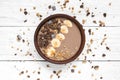 Bowl of chocolate cocoa banana protein smoothie with granola on white table