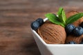 Bowl of chocolate ice cream and blueberries on wooden table, closeup Royalty Free Stock Photo