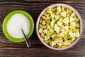 Bowl with chopped apples, spoon in bowl with sugar on table. Top view
