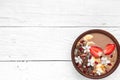 Bowl of cocoa smoothie with chocolate granola, banana, strawberry and pomegranate topped with flowers
