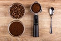 Bowl with coffee beans, holder from coffeemaker with ground coffee, bowl with ground coffee, spoon on table. Top view Royalty Free Stock Photo