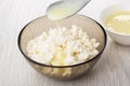 Bowl with condensed milk, spoon with milk above bowl of cottage cheese on table Royalty Free Stock Photo