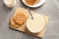 Bowl of condensed milk and waffles served on grey table, top view. Royalty Free Stock Photo